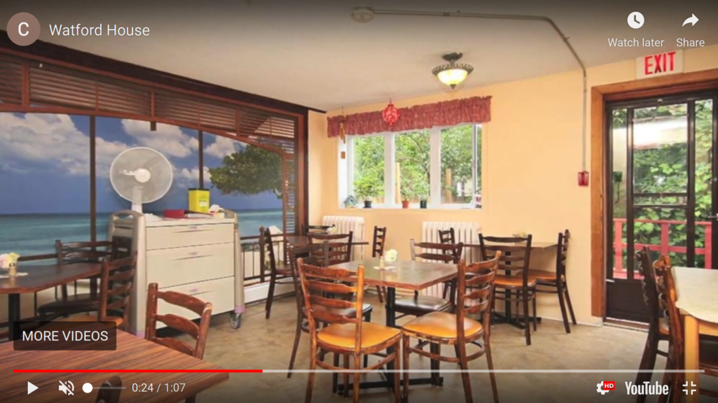 Image of a typical communal dining room (Watford House Ottawa, 2021) The image includes several small square tables with 4 wooden chairs around them.